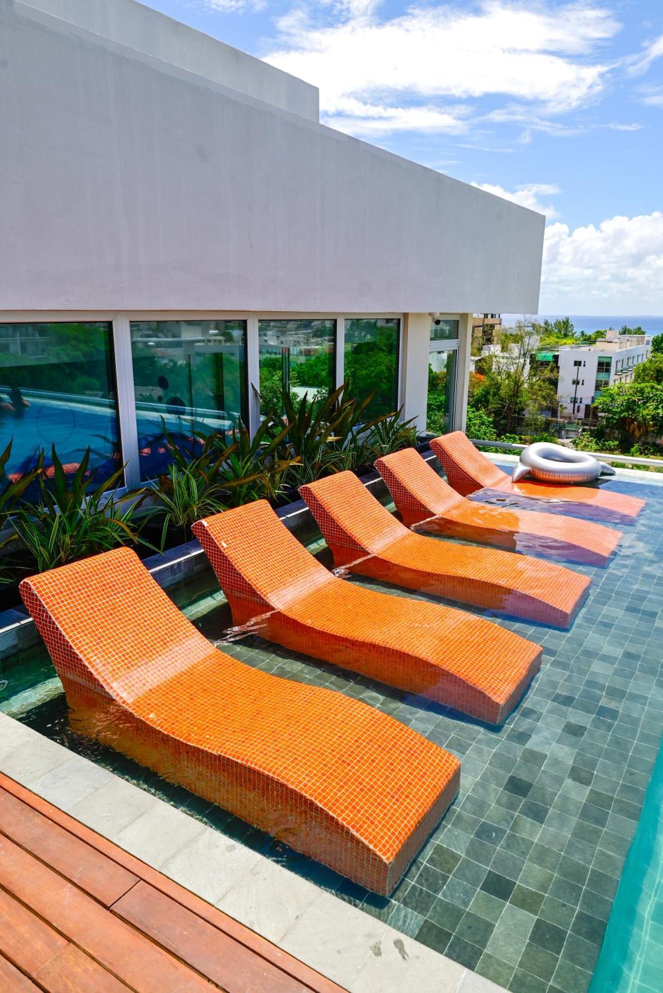 Aloft Playa Del Carmen Hotell Exteriör bild Sunbathing chairs at a pool